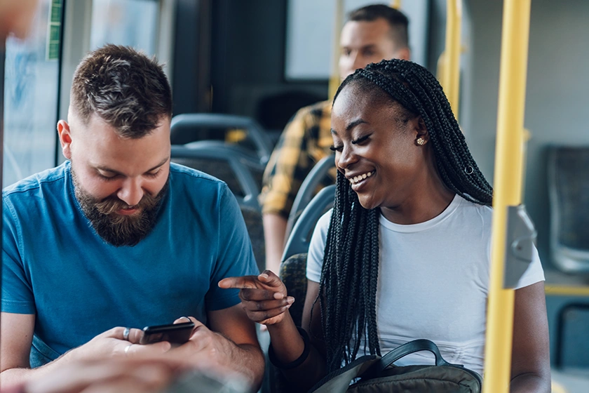 Inclusive and environmentally resilient places Couple chating and smiling while traveling on bus.